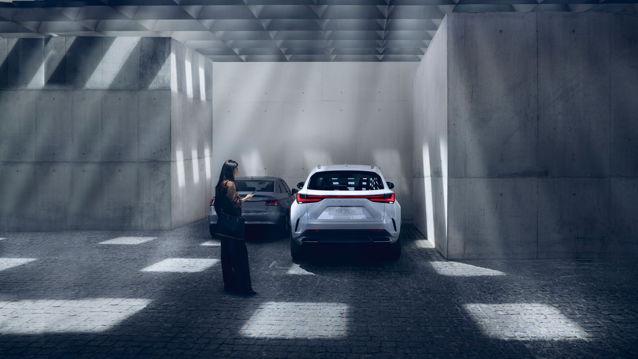 A woman using her mobile phone next to a Lexus NX 350h