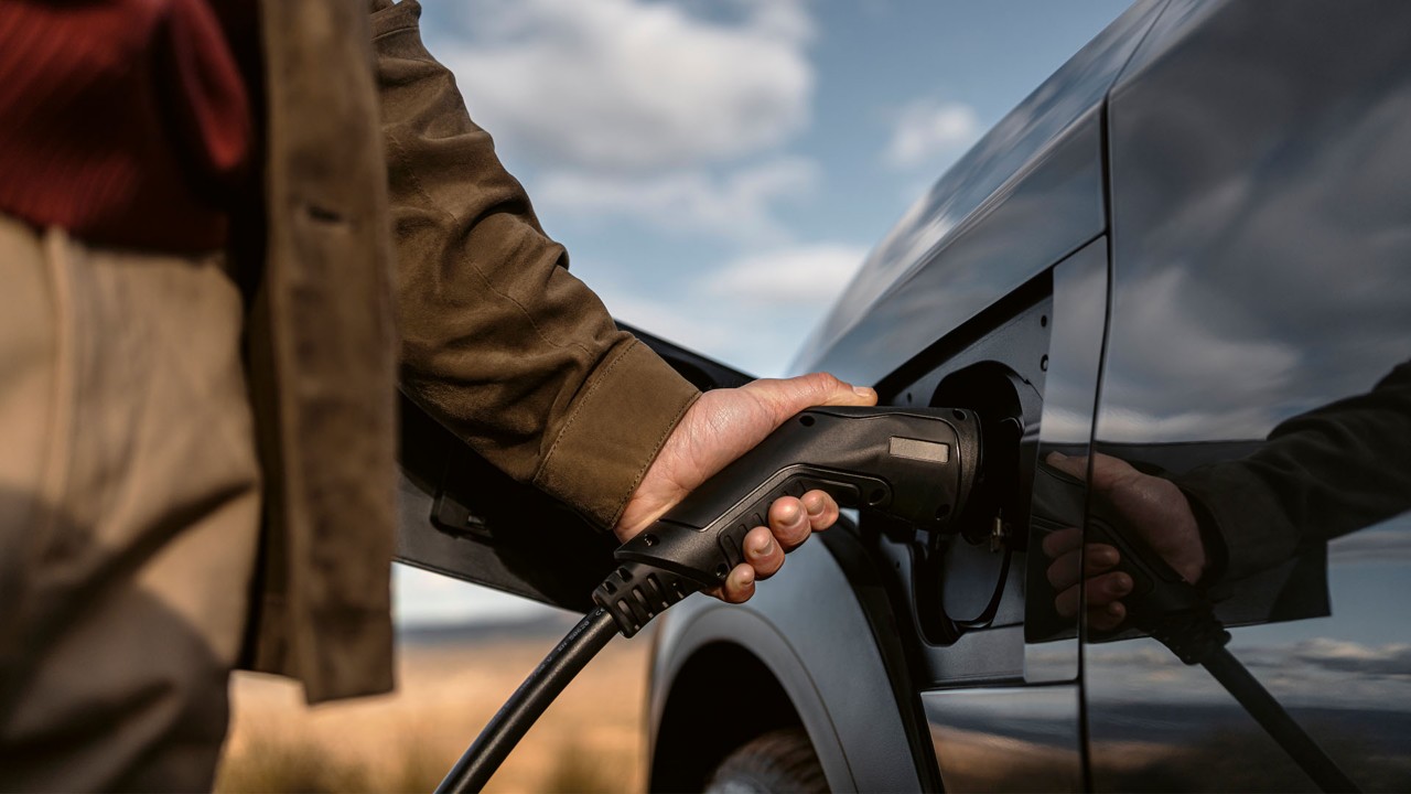 A man plugging in a charger to a Lexus RZ 450e