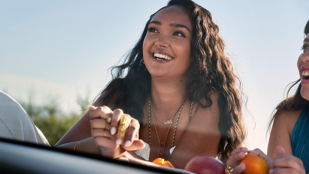 Joy Crookes leaning on the bonnet of a Lexus UX