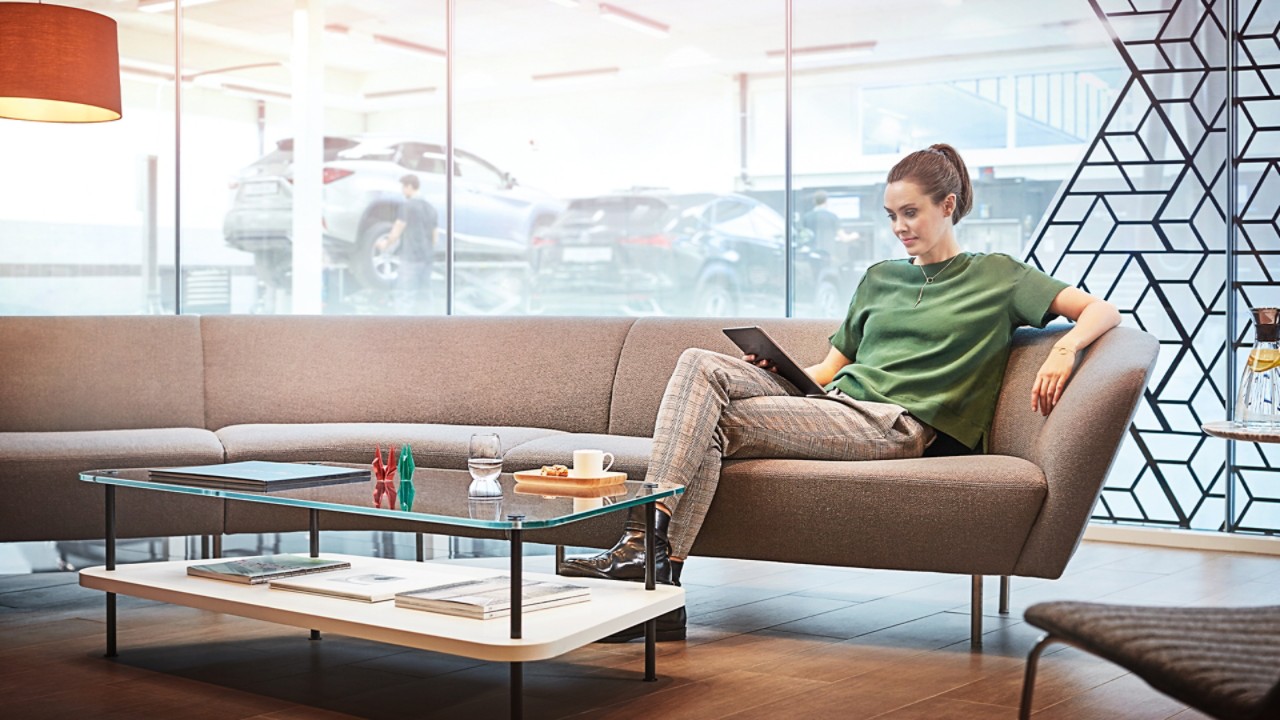 A woman sitting on a sofa in a Lexus dealership