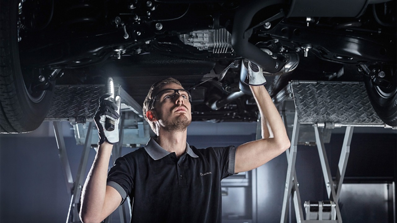 A Lexus mechanic working on a Lexus undercarriage